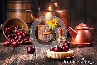 Small portion cheesecake with fresh sweet cherries against of cooper dish and scattered sweet cherries over on old wooden Stock Photo