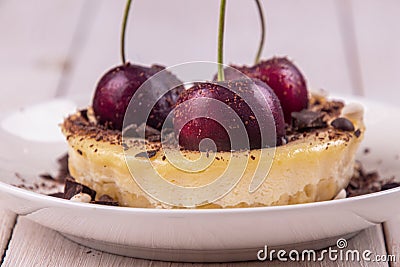 Small portion chessecake decorated with sweet cherries over on white wooden background Stock Photo