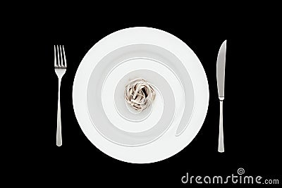 Small portion of tagliatelle pasta on round white plate with fork and knife on isolated black background. Stock Photo