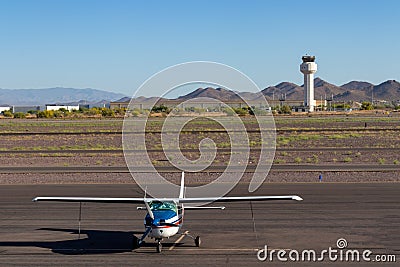 Small private airplane during early morning hours at airport with control tower in background Editorial Stock Photo