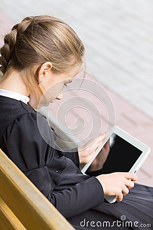 Small pupil girl with tablet sitting on bench Stock Photo