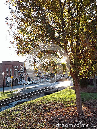 Sunset sunshine sun light Downtown buildings stores rail road small town quaint green trees Editorial Stock Photo