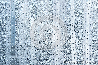 A small raindrop rests on the glass after rain. Raindrops On The Glass. Raindrops on the window. Blue tone. Abstract background. Stock Photo