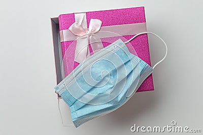 A small rectangular present gift box on a white background open with face mask on it Stock Photo