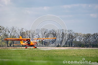 Small red charter airplane waiting on a green field to take off Stock Photo