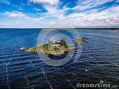 A small red cottage on an island in the blue sea on a summer day. Finland. View from above. Stock Photo