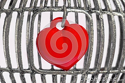 Small red heart locked inside a birdcage Stock Photo