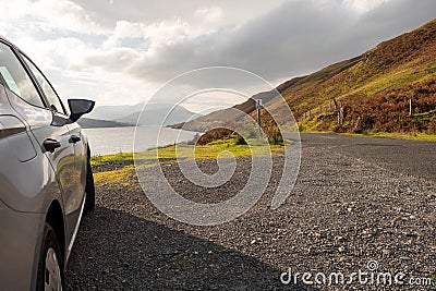 Small rented car parked off small road with beautiful scenery view. Killray fjord, county Mayo, Ireland. Cloudy sky, Mountains in Stock Photo