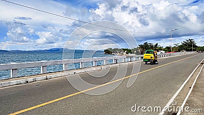 Small rickshaw riding through a road surrounded by the sea in Surigao Del Norte, the Philippines Stock Photo