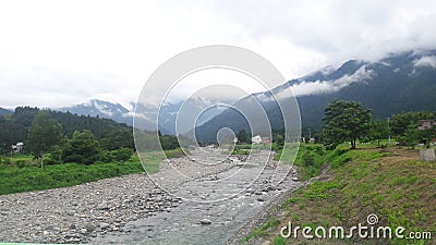 The small river with the background of the mountain covered with cloud Stock Photo