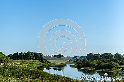 A small river in the middle of the field and green vegetation formed by the flood of the river Stock Photo