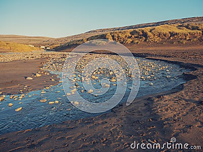 Small river by sand dunes, small cabins in the background. Concept living in remote location by nature Stock Photo