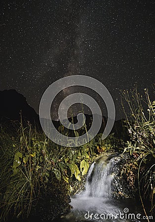 Small river stream waterfall in the mountains on a starry night against the background of the starry sky of the milky way at night Stock Photo