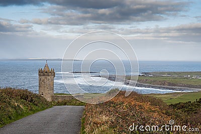 Small road leads to Doonagore castle, Doolin pier and Aran islands in the background. Beautiful cloudy sky. Popular tourist Stock Photo
