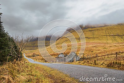 Small road into mountains Forest on the left empty fields and small abandoned house on the right. Geniff Horseshoe loop drive Stock Photo