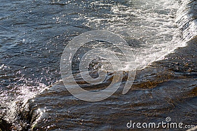A small roll on a mountain river, a threshold, glare on clear water Stock Photo