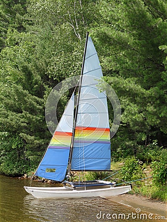 Small sailboat on shore of a lake. Stock Photo