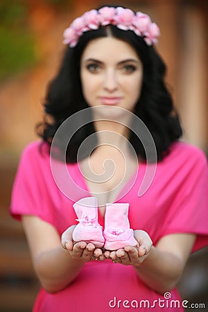 Small shoes for the unborn baby in the hand of pregnant woman is Stock Photo