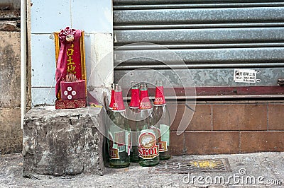 Small shrine to the earth god Tu Di and beer bottles on a Hong Kong street. The text reads `the doorway to the Earth God.` Editorial Stock Photo