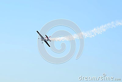 The small smoking plane flies in the sky. Stock Photo