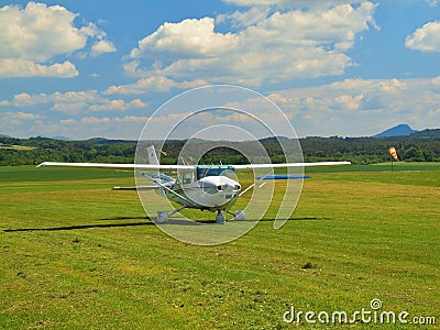 Small sport airplane is rolling or moving on grass airport.Tree edge propeller is quickly turning Editorial Stock Photo