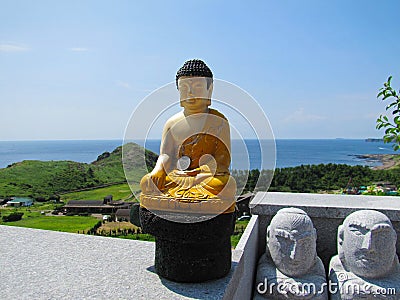 Small statue of buddha wearing yellow clothes and with a silver coin on the left hand Stock Photo