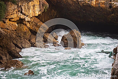 Small statue on seacoast in evening sunlight. Rocky cave in coast of Atlantic Ocean. Coastal nature. Cantabria landscape at sunset Editorial Stock Photo