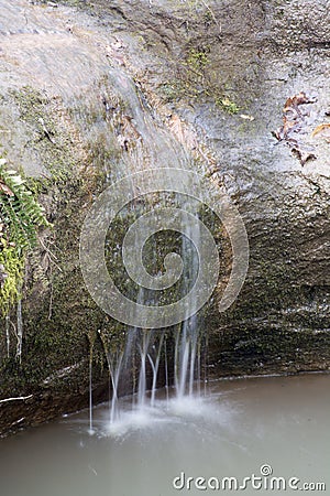 Small waterfall over large mossy rock Stock Photo