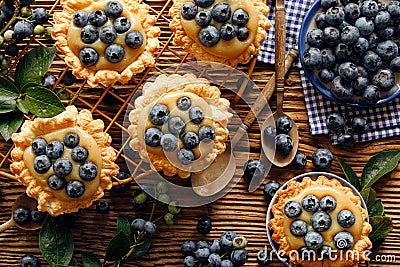 Small tarts made of puff pastry with addition fresh blueberries and caramel chocolate custard on a wooden rustic table, top view, Stock Photo