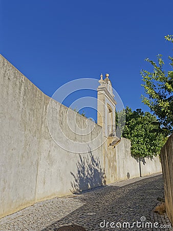 A small Terrace with Iron Railings overlooking a small Cobbled Street below the walls of the Palace of Estoi. Stock Photo