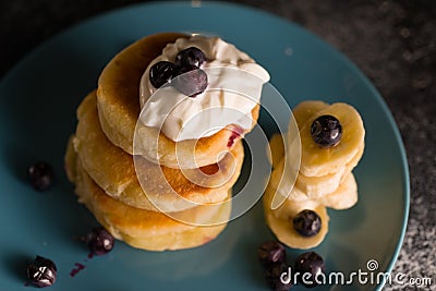 Small thick pancake with berries and sour cream on a beautiful blue plate home cooking tomorrow with goodies Stock Photo