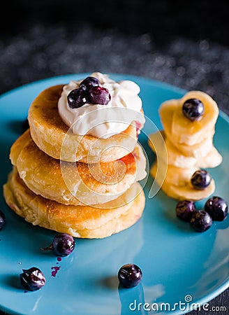 Small thick pancake with berries and sour cream on a beautiful blue plate home cooking tomorrow with goodies Stock Photo