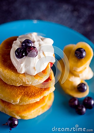 Small thick pancake with berries and sour cream on a beautiful blue plate home cooking tomorrow with goodies Stock Photo