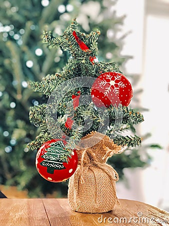 Small tiny christmas tree and red ornaments big and lights tree in background Stock Photo