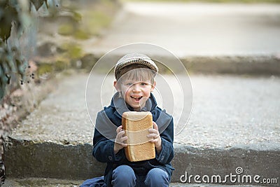 Small toddler is holding a large loaf of bread. Stock Photo