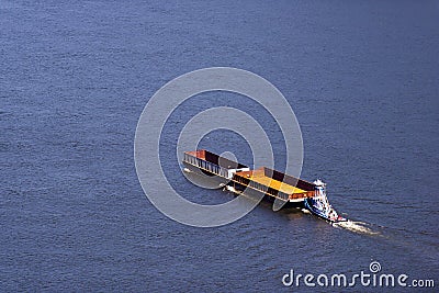 Small towboat pushing two empty barges on broad river Stock Photo