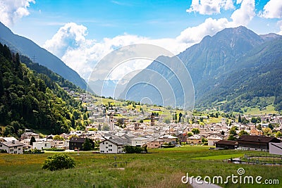 Small town in green summer valley surrounded by mountains in Swiss alps Stock Photo
