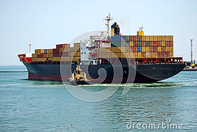The small tugboat near the big ship Stock Photo