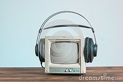 A small video surveillance monitor on a wooden table with black headphones. Stock Photo