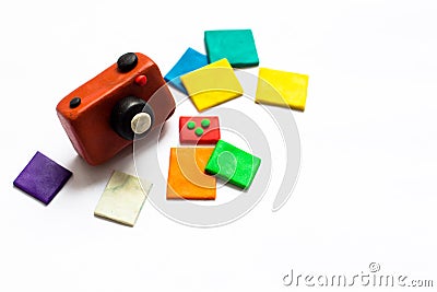 A small vintage camera of brown color is made of plasticine. Next to the camera is a few photos of bright and colorful flowers. Stock Photo