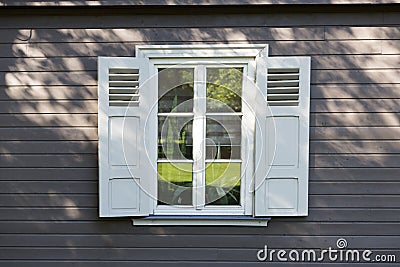 Small vintage white window with shutters on wooden grey wall Stock Photo