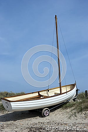 Small white boat on sandy dune by the sea Stock Photo