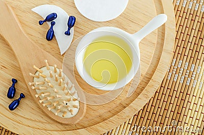 Small white bowl with cosmetic massage, cleansing oil, face serum capsules and wooden hairbrush. Natural haircare and spa Stock Photo