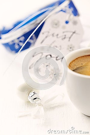 Small, white Christmas bauble, blue ribbon and a cup of coffee. Stock Photo