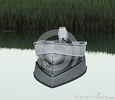 Small white motor boat mored reflecting in lake water Stock Photo