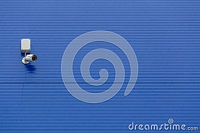 Small white security camera on large blue steel silo wall Stock Photo