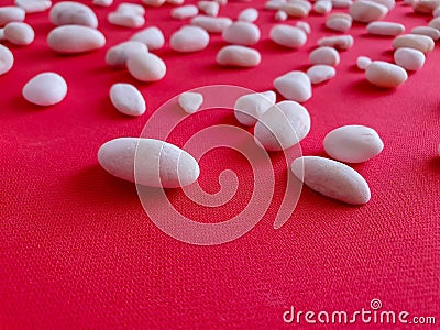 Small white stones on the bright coral fabric. Texture, background, pattern, wallpaper. ok Stock Photo