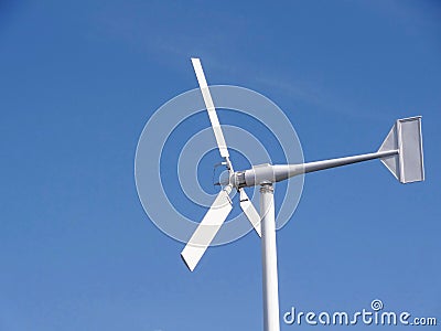 Small white wind turbine, windmill alternative Green clean energy against blue sky Stock Photo