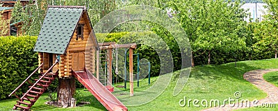 Small wood log playhouse hut with stairs ladder and wooden slide on children playground at park or house yard. Panoramic Stock Photo