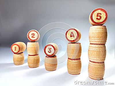 Small wooden barrels with numbers built in uneven columns. The concept of uneven movement on the way to achieving the Stock Photo
